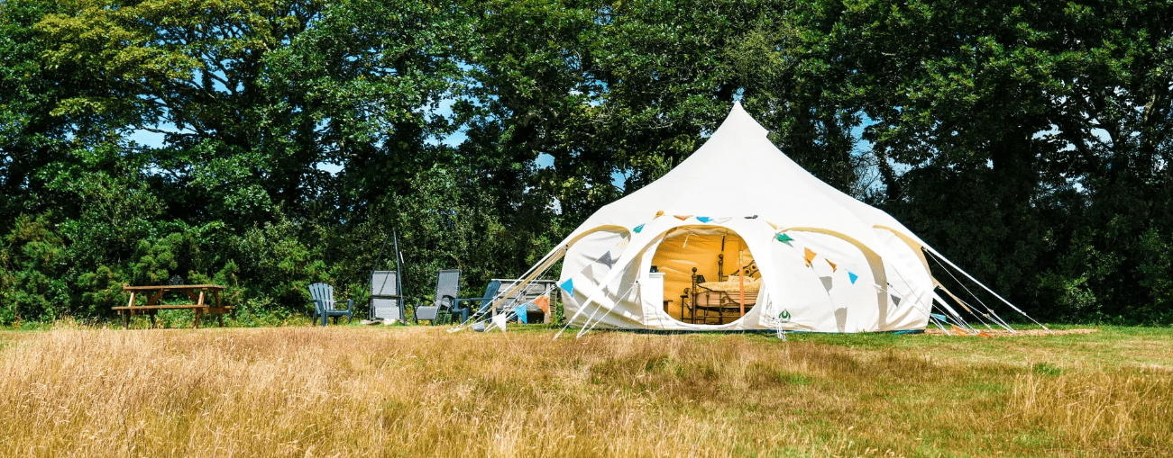 Image of a Lotus Belle bell tent pitched in a field. A luxury, canvas tent with lots of standing room & made from bespoke canvas. Perfect for camping & glamping.